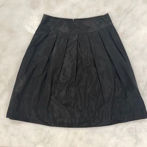 Black A-line skirt with pleating detail.
